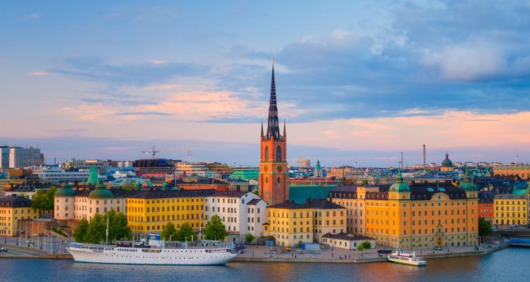 Avondzicht op Stockholm's Riddarholmen met hoge kerktoren en kleurrijke gebouwen aan de waterkant.