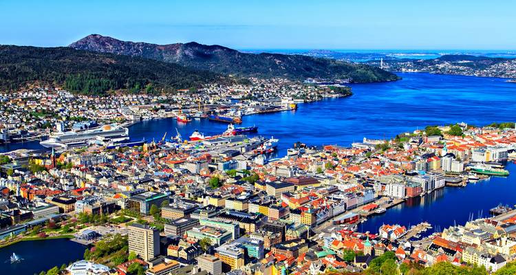 Weite Luftaufnahme von Bergens farbenfrohem Stadtzentrum und geschäftigem Hafen, umgeben von tiefblauem Fjord.