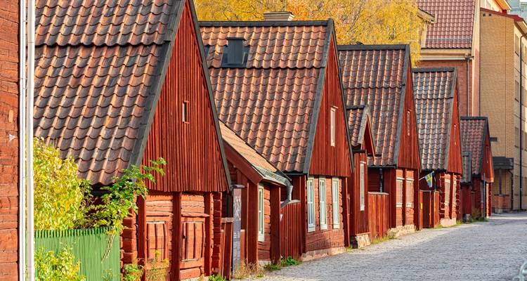 Kopfsteinpflasterstraße gesäumt von traditionellen roten Fachwerk-Bergarbeiterhäusern im Herbstlicht.