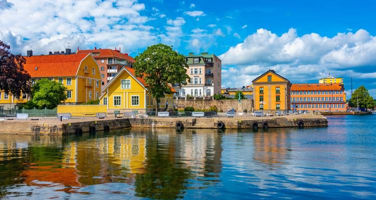 Bâtiments historiques colorés du front de mer de Karlskrona reflétés dans l'eau bleu vif du port.