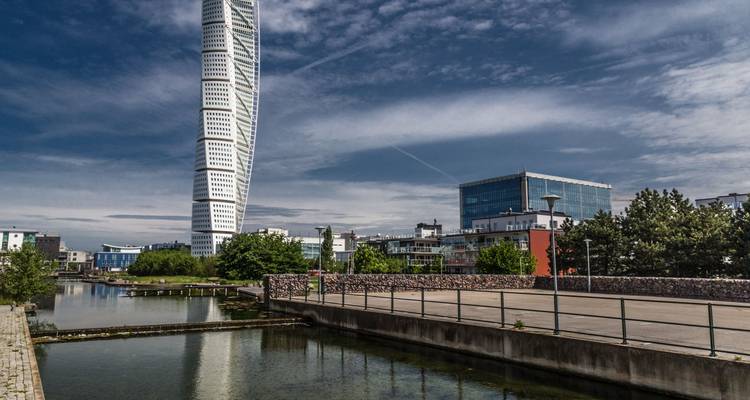 La tour distinctive Turning Torso de Malmö s'élevant au-dessus d'un canal et d'un quartier moderne.