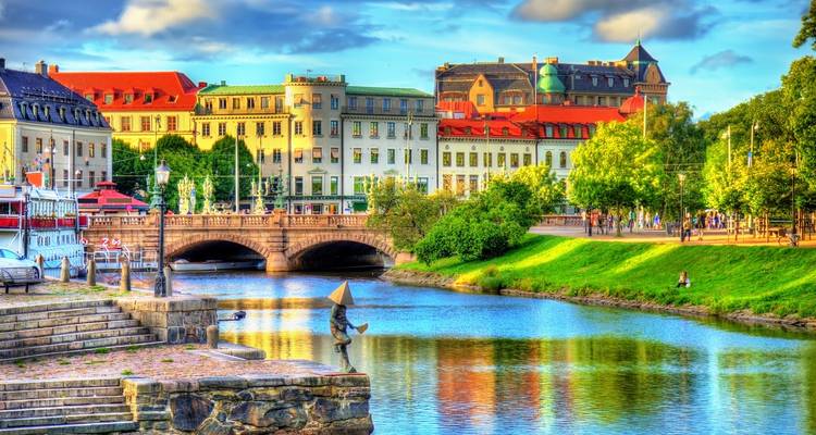 Scène colorée au bord de la rivière à Göteborg avec un pont en pierre, des bâtiments historiques et des reflets dans le canal.