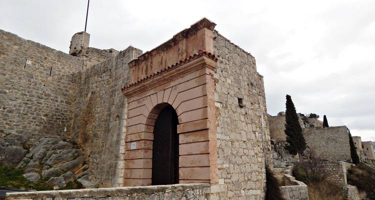 Portail d'entrée en pierre avec une porte voûtée intégrée dans les murs d'une forteresse par un jour nuageux.