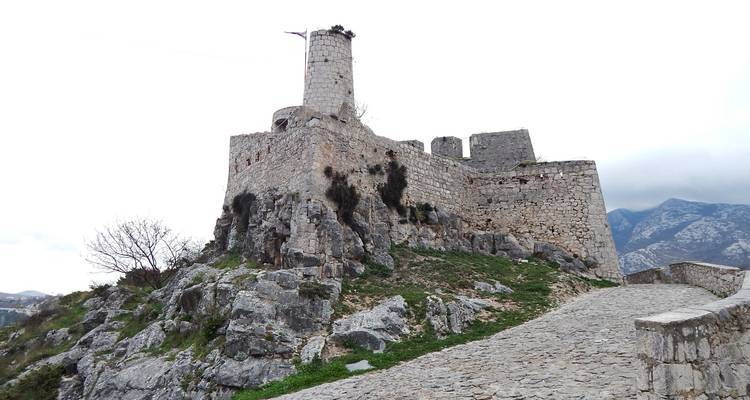 Steinrampe führt zu den zerklüfteten Ruinen und dem Turm der Festung Klis, die auf einem felsigen Grat thront.