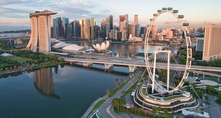 Luchtfoto bij dageraad van Marina Bay met Singapore Flyer, ArtScience Museum en skyline gespiegeld in kalm water.