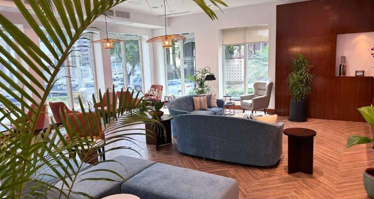 Salon d'hôtel moderne doté de sièges moelleux, d'un plancher en parquet et de grandes fenêtres donnant sur la circulation urbaine.
