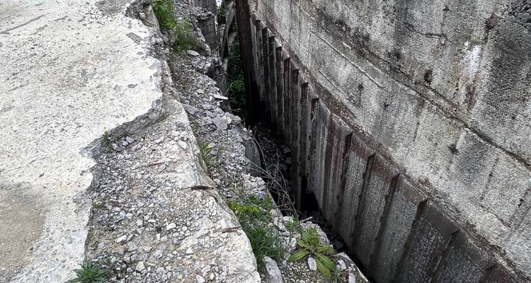 Fisura profunda y muros de concreto desmoronándose de una estructura abandonada llena de escombros