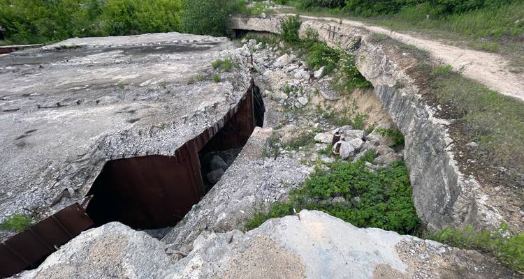 Vista amplia de un techo de concreto colapsado que expone paredes de acero oxidado y escombros esparcidos
