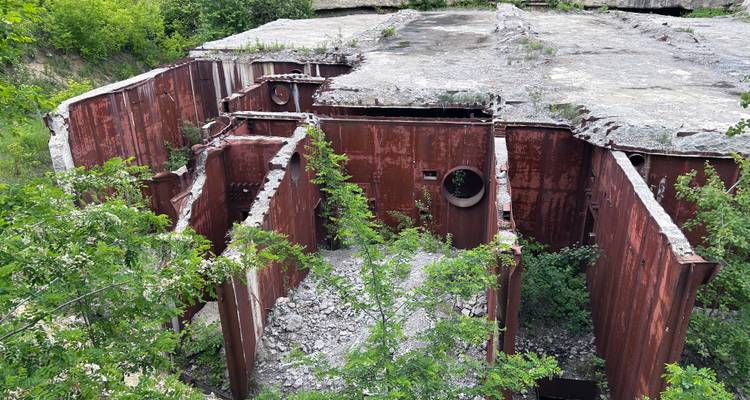 Carcasa interior de paredes de búnker de metal oxidado con techo de concreto colapsado y escombros