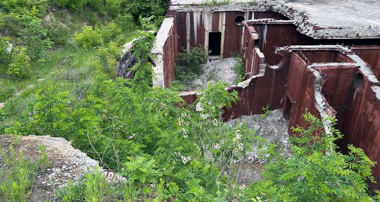 Vista hacia abajo de compartimentos de búnker oxidados y cubiertos de vegetación parcialmente demolidos