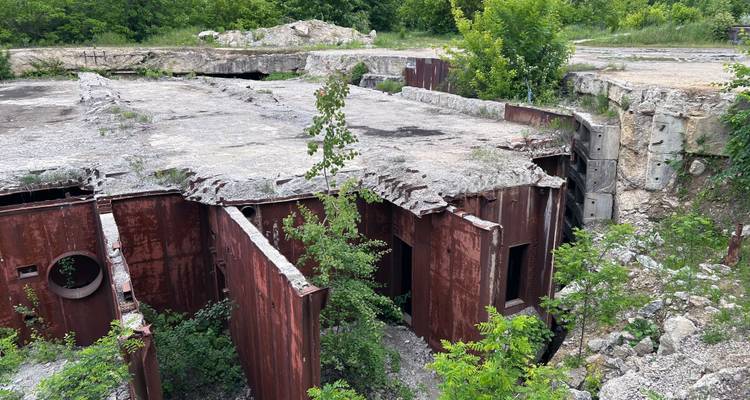 Vista cenital de una losa de concreto fracturada que descansa sobre paredes de búnker de acero corroído