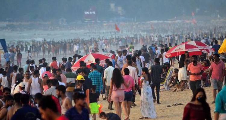 Überfüllter tropischer Strand voller Urlauber, Sonnenschirme und dunstige Küstenlinie