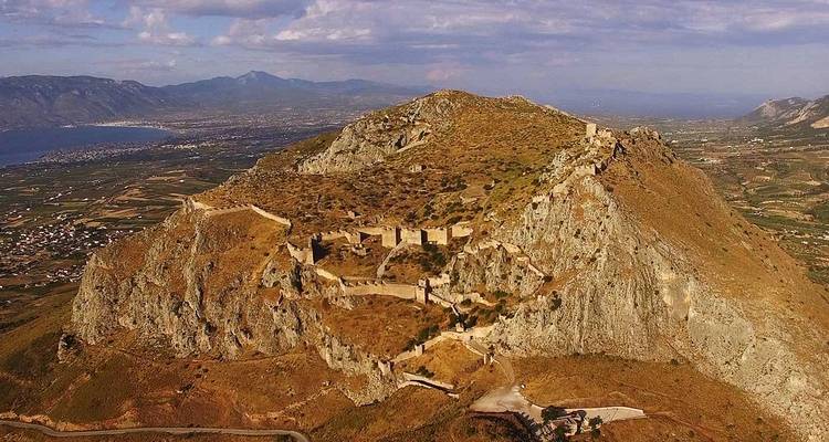 Vue aérienne élevée de la forteresse fortifiée d'Acrocorinthe au sommet d'une montagne rocheuse surplombant les plaines et la mer.