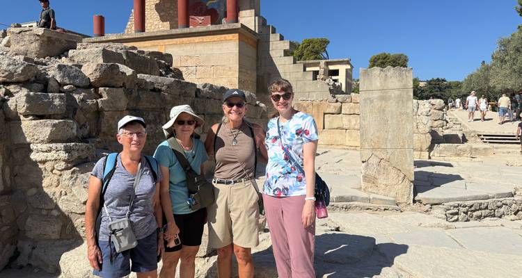 Quatre voyageurs se tiennent parmi d'anciennes ruines de pierre sous un ciel bleu éclatant.