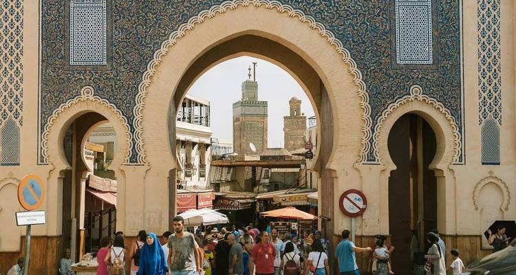 Foule animée traversant la porte ornée de carreaux bleus Bab Bou Jeloud pour entrer dans la médina de Fès.