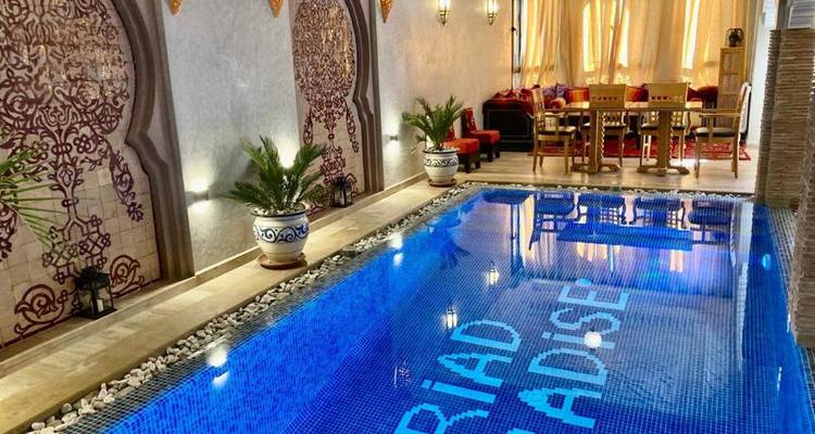 Piscine élégante de riad intérieur avec carreaux de mosaïque bleue et coin salon avec coussins.