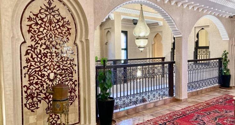 Corridor voûté orné à l'intérieur d'un riad marocain avec lanterne suspendue et carreaux à motifs.