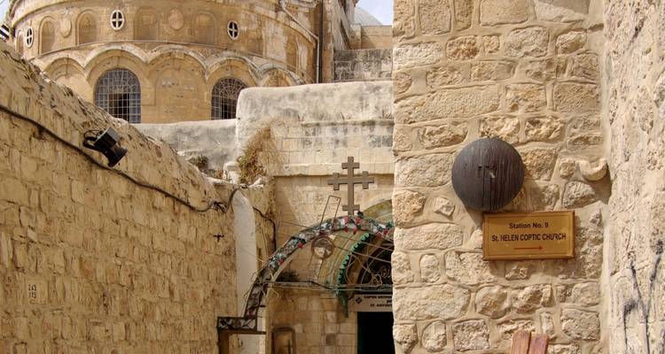 Ruelle étroite en pierre sur la Via Dolorosa avec signalisation et les murs de l'église du Saint-Sépulcre
