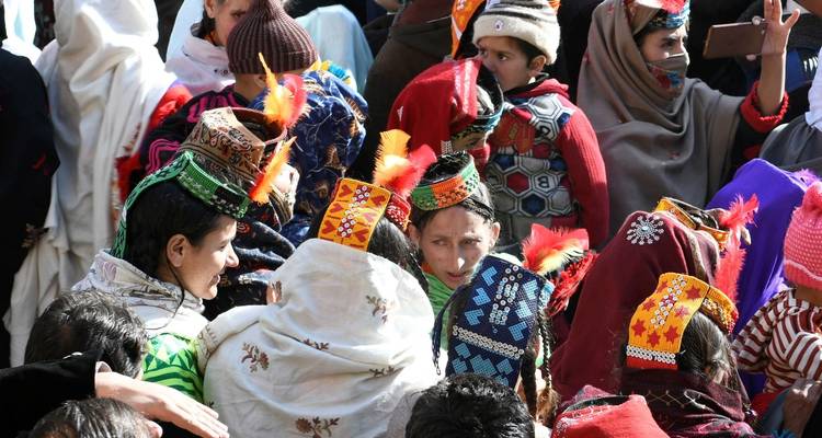Menschenmengen in bunter traditioneller Kleidung versammeln sich dicht gedrängt während einer lebendigen Feier im Freien.
