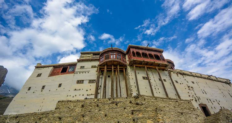 Die historische Baltit-Festung mit verzierten Holzbalkonen erhebt sich vor einem Hintergrund aus blauem Himmel und dünnen Wolken.