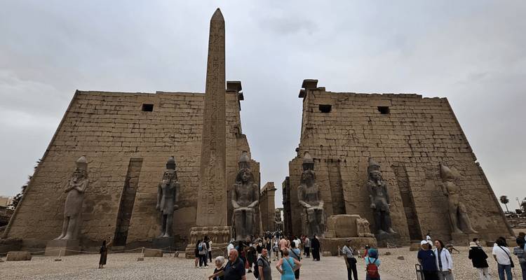 Los turistas se reúnen frente a los pilones masivos y el obelisco del Templo de Luxor en un día nublado.