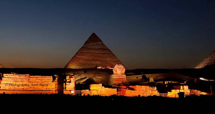 Vista nocturna de las pirámides y la Esfinge iluminadas durante un espectáculo de sonido y luz.
