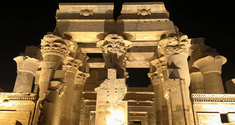 Columnas y capiteles del Templo de Kom Ombo iluminados con focos cálidos durante la noche.