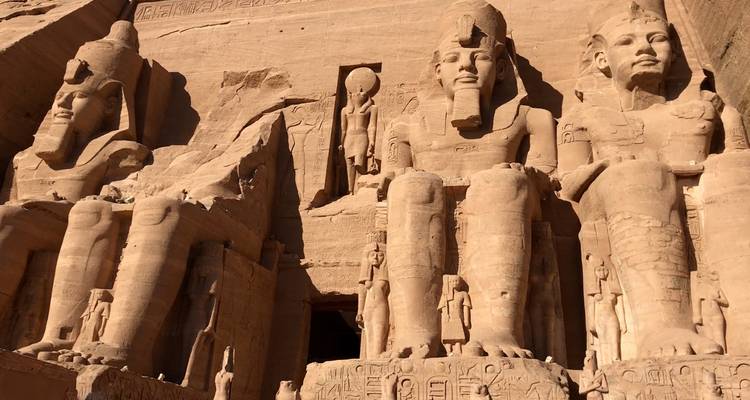 Vista cercana de las colosales estatuas sedentes de Abu Simbel talladas en arenisca rosa.