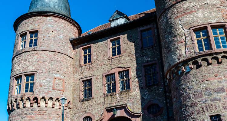 Close-up of a medieval red-stone castle tower with blue sky backdrop in southern Germany.