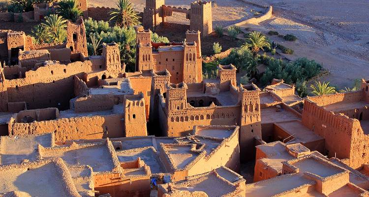 Vista aérea de las torres de adobe del kasbah y patios del antiguo Ait Benhaddou rodeado de palmeras.