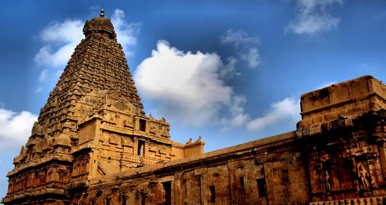 The towering Brihadisvara Temple’s ornate stone vimana rises dramatically against a blue sky.