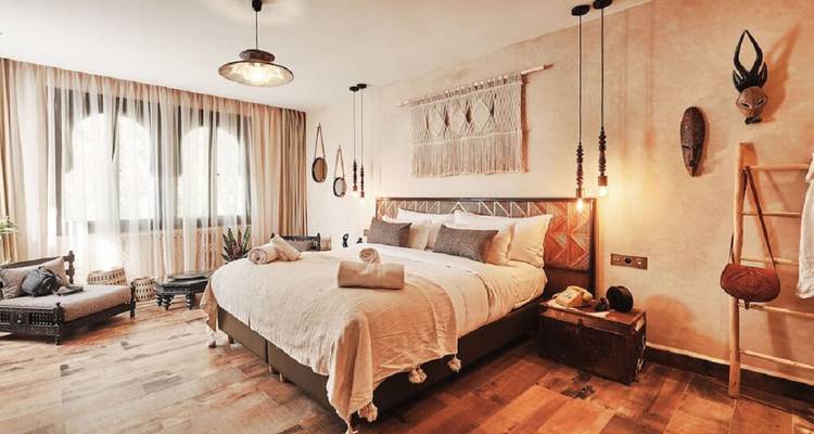 Stylish riad bedroom with earthy décor, woven wall art and warm lighting.