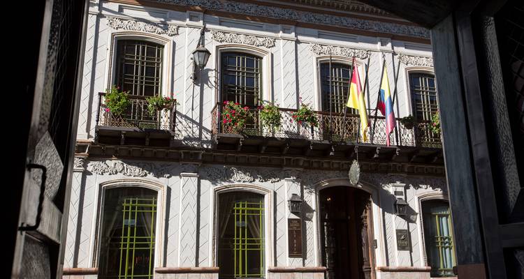 Elegante fachada colonial con balcones tallados y banderas nacionales en el centro histórico.