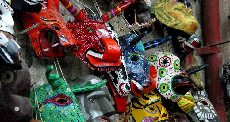 Fila de máscaras tradicionales vívidas pintadas a mano colgando en exhibición.