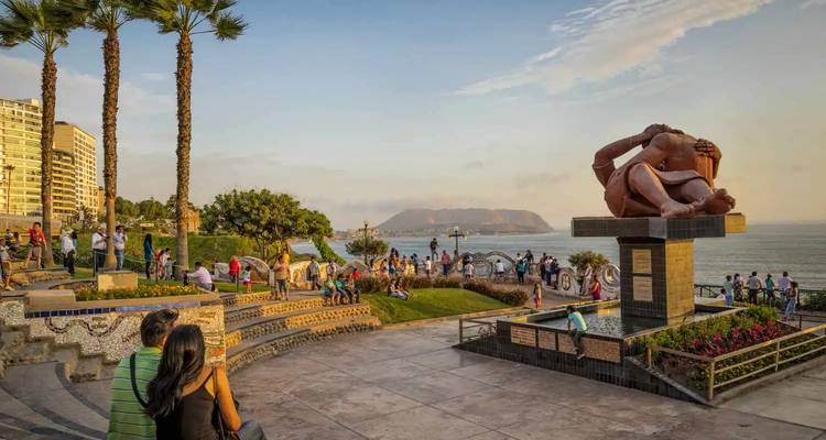 Menschenmengen genießen den Sonnenuntergang in Limas Parque del Amor mit Meerblick und der El Beso-Skulptur.