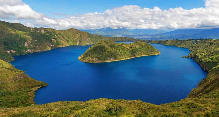 Vista aérea vívida del Lago Cuicocha con agua azul profunda e isla volcánica exuberante bajo nubes dispersas.