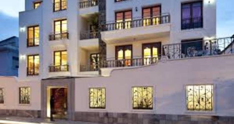 Exterior de un pequeño hotel boutique con ventanas iluminadas y barandillas decorativas de hierro forjado al anochecer