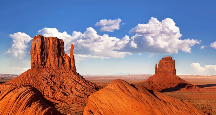 Ikonische rote Sandsteinberge, die sich vom Wüstenboden unter einem klaren blauen Himmel erheben.