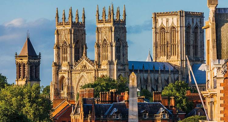 Les tours ornées de York Minster s'élèvent au-dessus des toits historiques en brique baignés dans la lumière du soir.