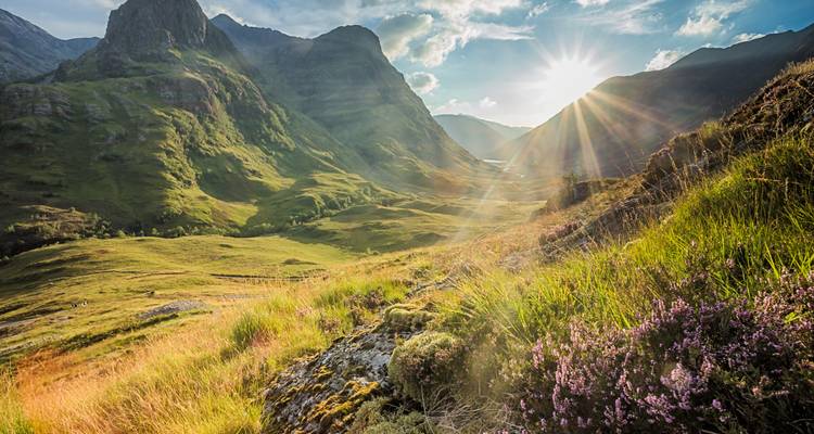 Des rayons de soleil illuminent les montagnes vertes spectaculaires et le fond de vallée de Glencoe, dans les Highlands écossaises.