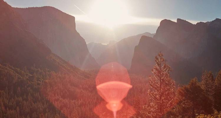 Escena duplicada del Valle de Yosemite al amanecer con destello de lente dramático y acantilados silueteados.