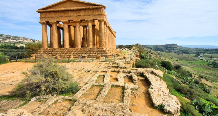 Temple grec antique bien conservé avec de hautes colonnes doriques surplombant une vallée sicilienne verdoyante