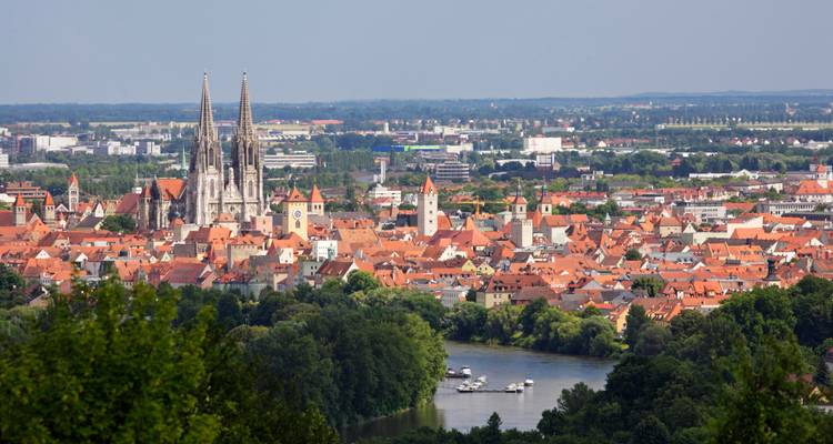 Vue lointaine de la vieille ville de Ratisbonne avec sa cathédrale aux tours jumelles s'élevant au-dessus des toits orangés au bord de la rivière.