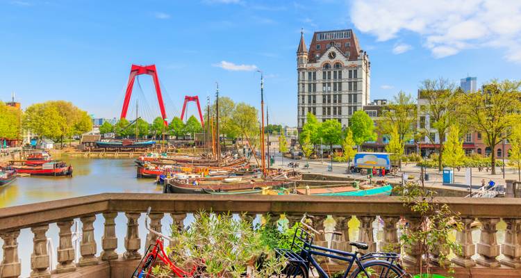 Uitzicht over de haven van Rotterdam met traditionele boten en de rode Willemsbrug op de achtergrond.