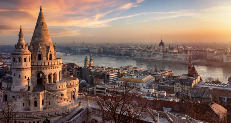 Sonnenaufgang über Budapest mit den Türmen der Fischerbastei, die über der Donau und dem ungarischen Parlament aufragen.