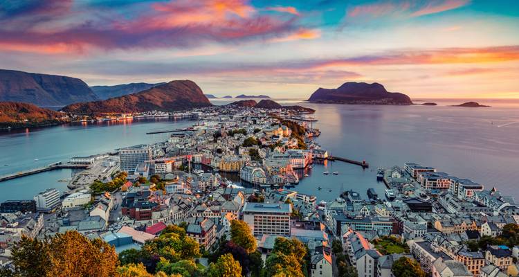Stunning sunset aerial panorama of Ålesund peninsula set between fjords and mountains.
