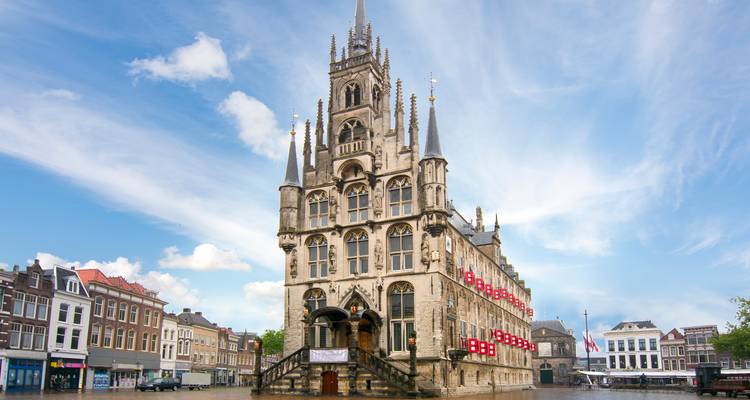 Ornate Gothic Gouda City Hall rises above a spacious Dutch square under streaked clouds.