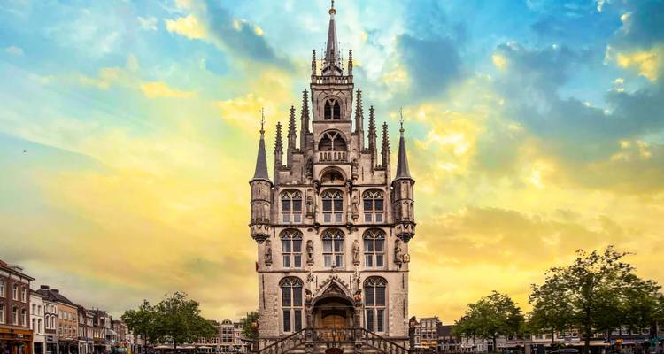 La façade gothique ornée de l'hôtel de ville de Gouda s'élevant de manière spectaculaire contre un ciel en fin de journée aux couleurs vives.