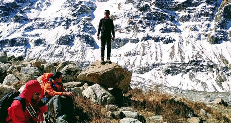 Trekkkers rusten tussen rotsen met hoge gestreepte ijsmuren achter hen in het hoge Himalayagebergte.