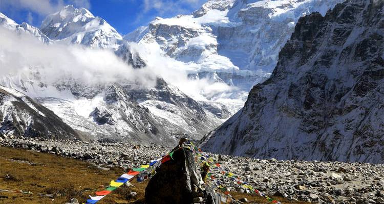 Sneeuw bedekt Himalaya-dal met kleurrijke gebedsvlaggen die wapperen onder een blauwe hemel.